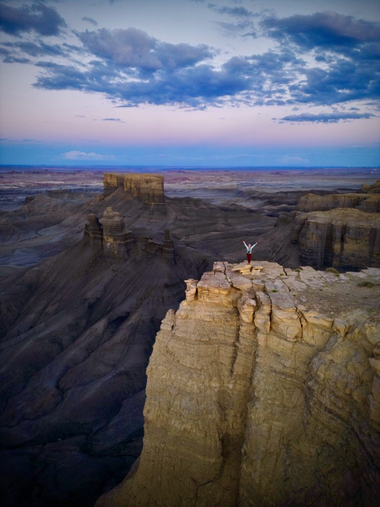 a girl standing on a cliff at Skyline View at Moonscape Overlook in Hanksville, Utah
