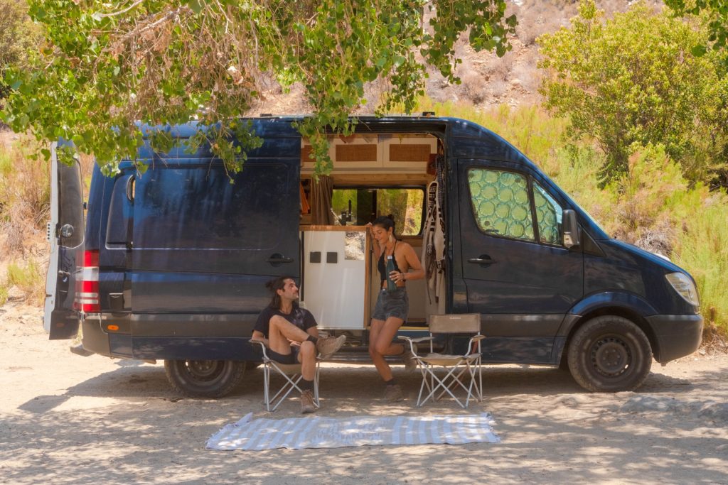A couple is hanging out side their Mercedes Sprinter Campervan.