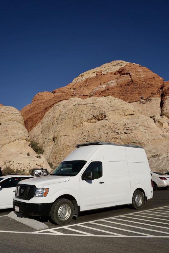 A white Nissan NV High Roof against sandstone background.