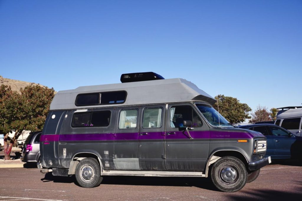 An old Ford conversion van has an aftermarket hightop, making it one of the best vans to live in.