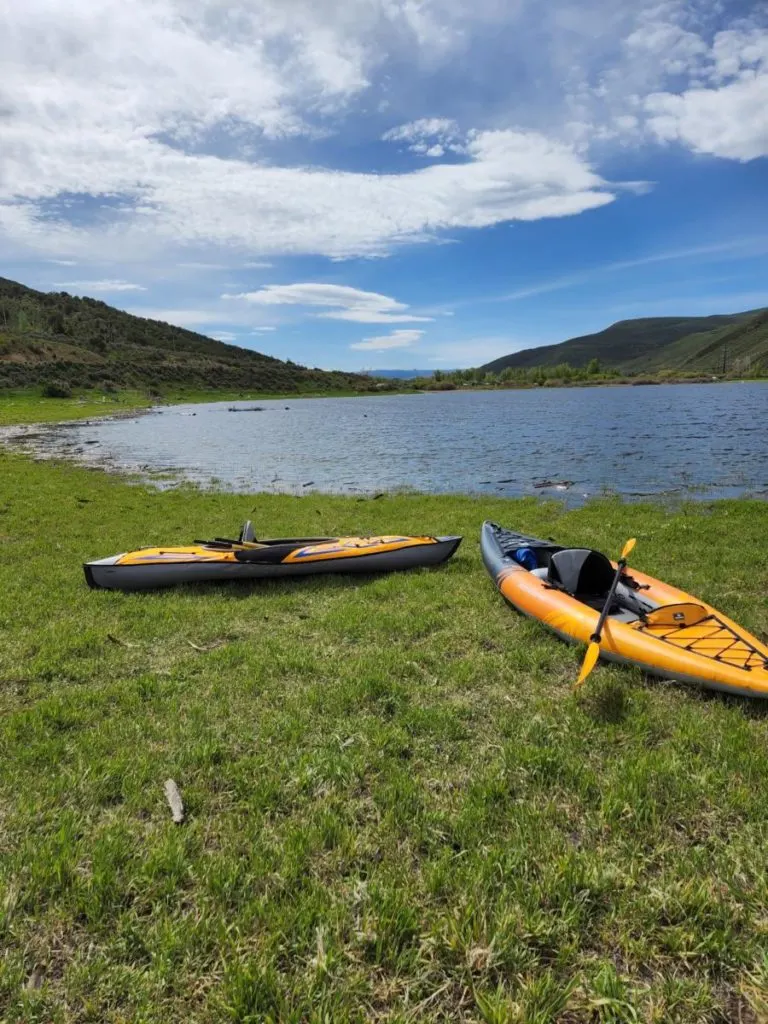 the aquaglide deschutes lightweight kayak on a grassy shore of a lake