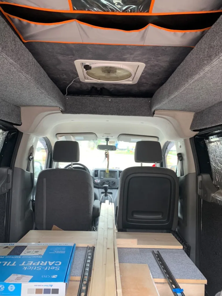 Interior view of installing a custom pop-up roof in a Nissan NV200 van conversion.