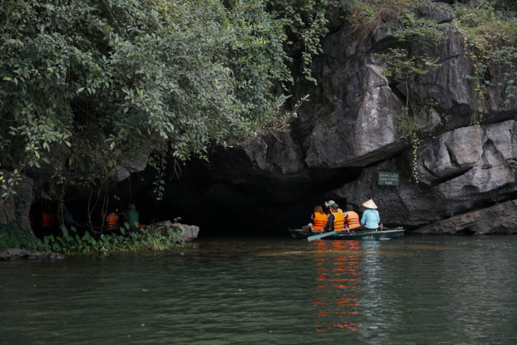 Tourists going under Lam Cave on Route 2 of the Trang An Boat Tour