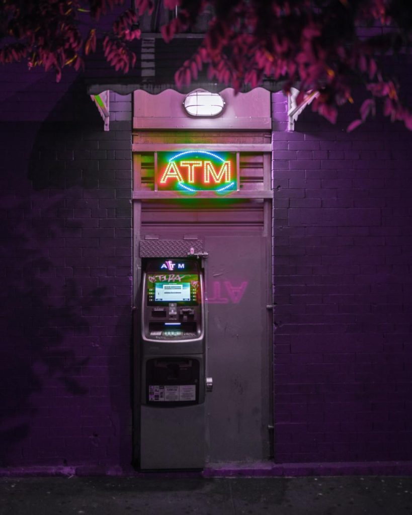 an atm lit up at dark with a neon light