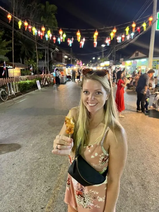 Emily eating Chicken Satay from a street vendor in Pai, Thailand