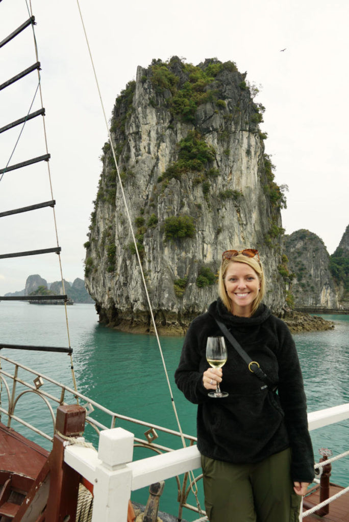 Emily enjoying a glass of wine on a Halong Bay Cruise in front of a limestone pillar