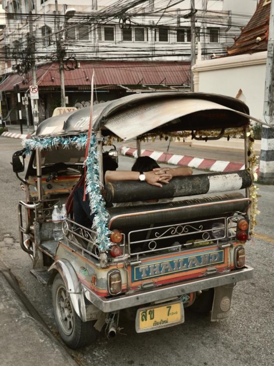a guy resting in his tuk tuk taxi in thailand