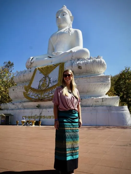 Emily renting a skirt from the locals at Big Buddha in Pai, Thailand because she has shorts on, which is One of the most important things to know when traveling to Thailand