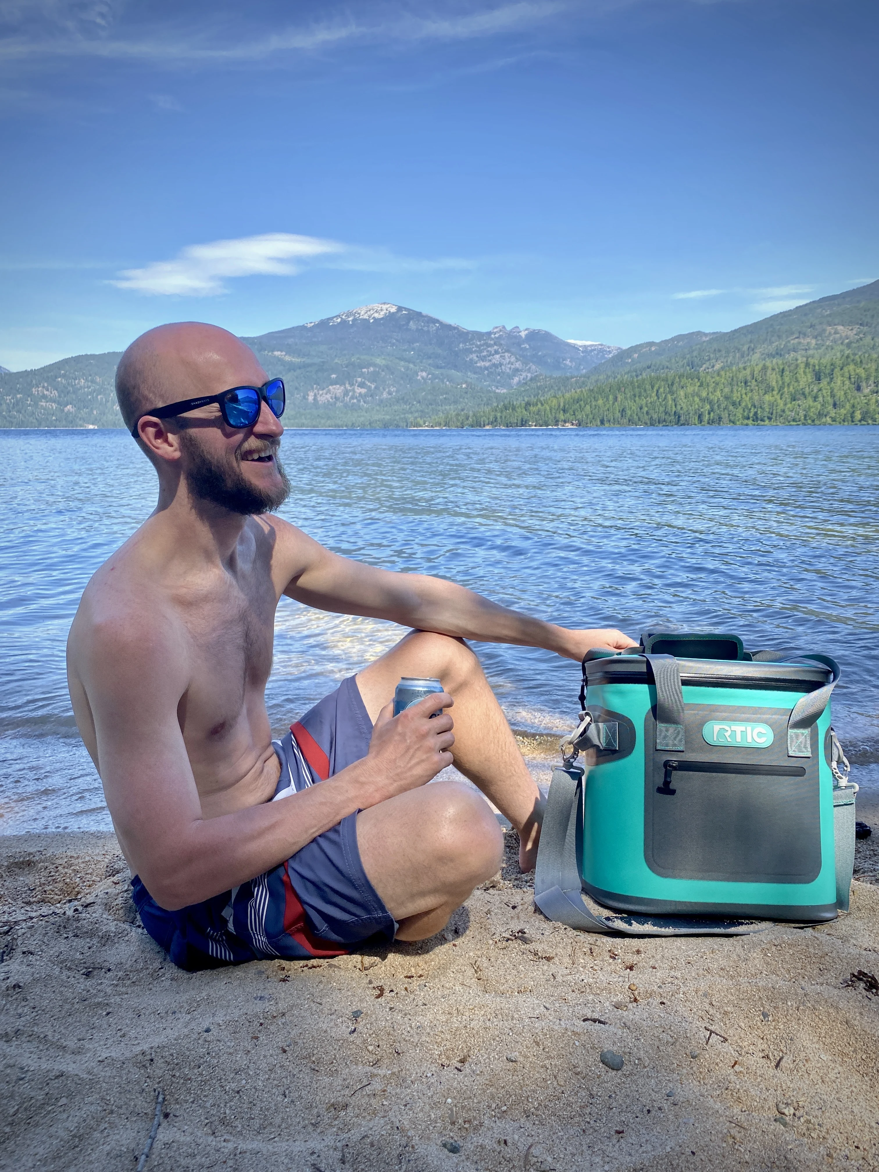 Jake sitting on the beach with an rtic cooler which is the perfect piece of camping gear under $20