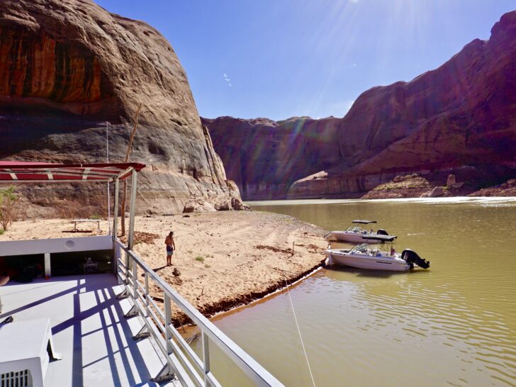 A houseboat and two powerboats anchored in Escalante Canyon