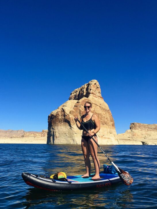 Emily paddle boarding in Wahweap Bay in front of Lone Rock.