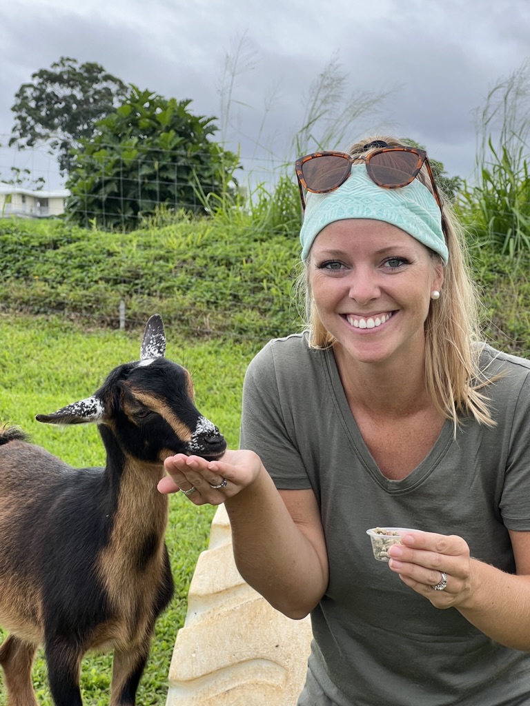 Emily feeding a goat in her Unbound Merino V-Neck