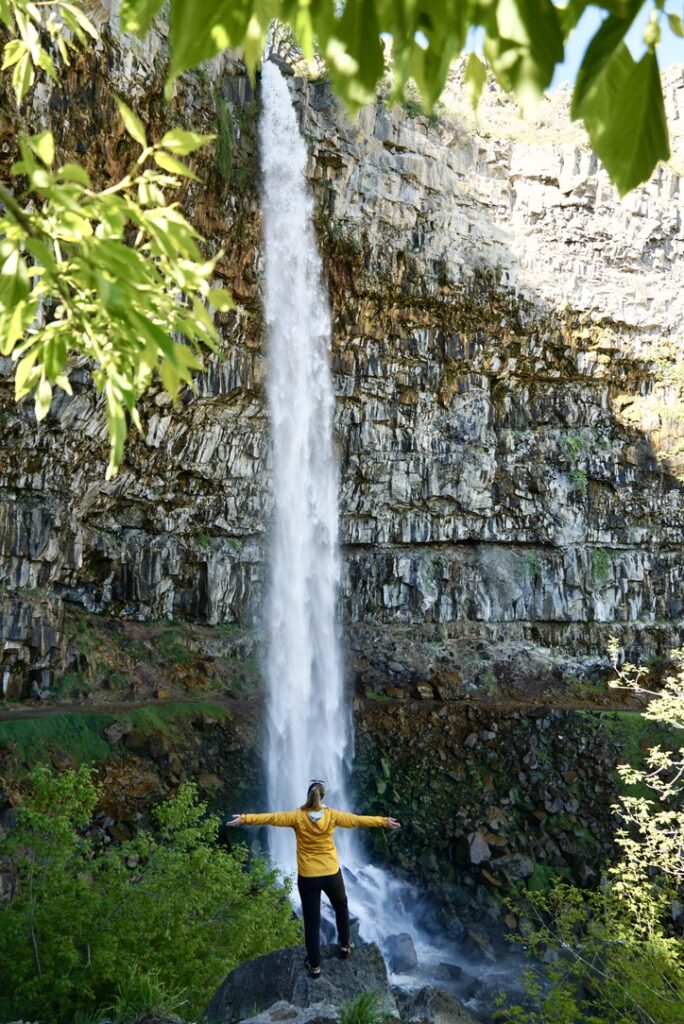 a girl opening her arms in front of Perrine Coulee Falls