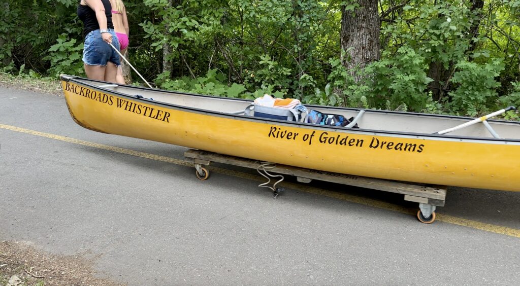 3 girls portaging their canoe to the other put in location along the River of Golden Dreams