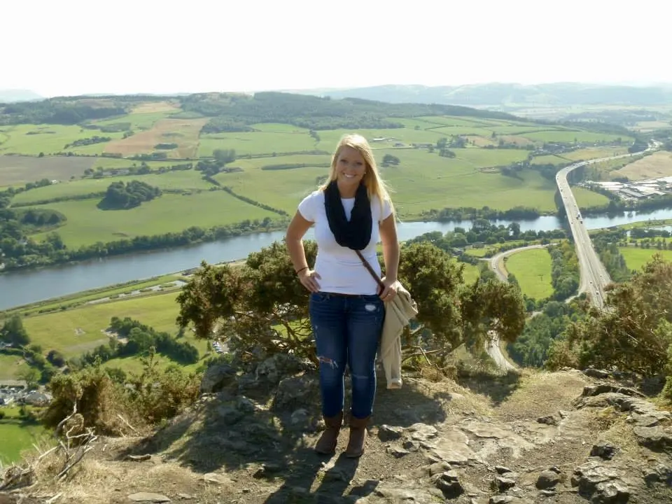 Emily standing in front of beautiful green fields in Perth, Scotland