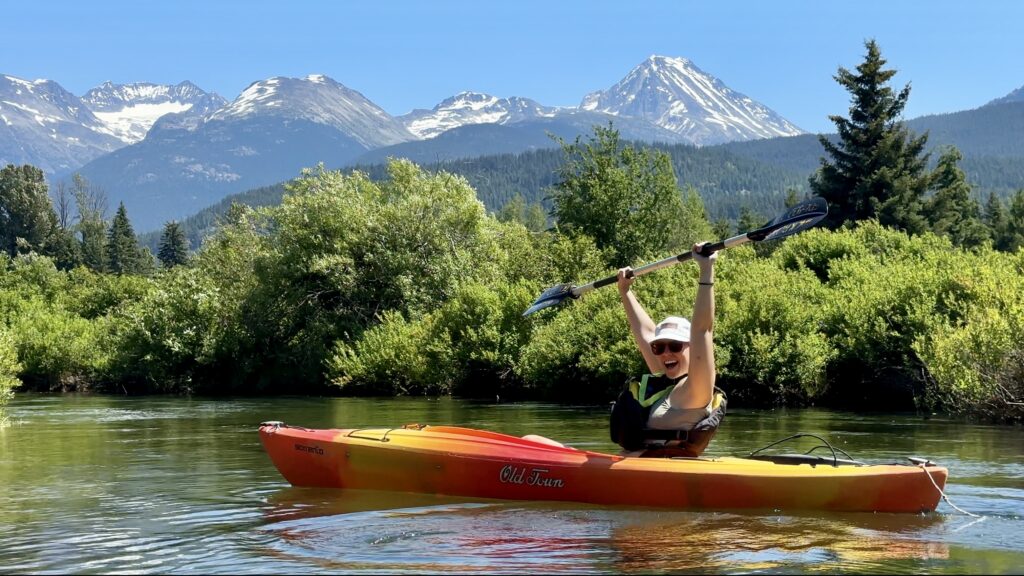 Emily throwing her hands up with the epic mountain views of the River of Golden Dreams