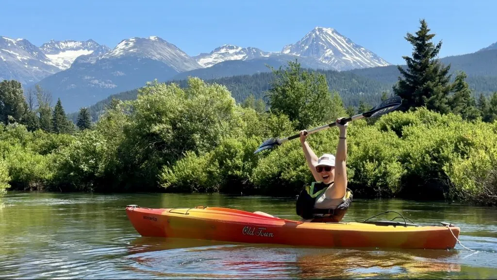 Emily throwing her hands up with the epic mountain views of the River of Golden Dreams