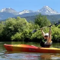 Emily throwing her hands up with the epic mountain views of the River of Golden Dreams