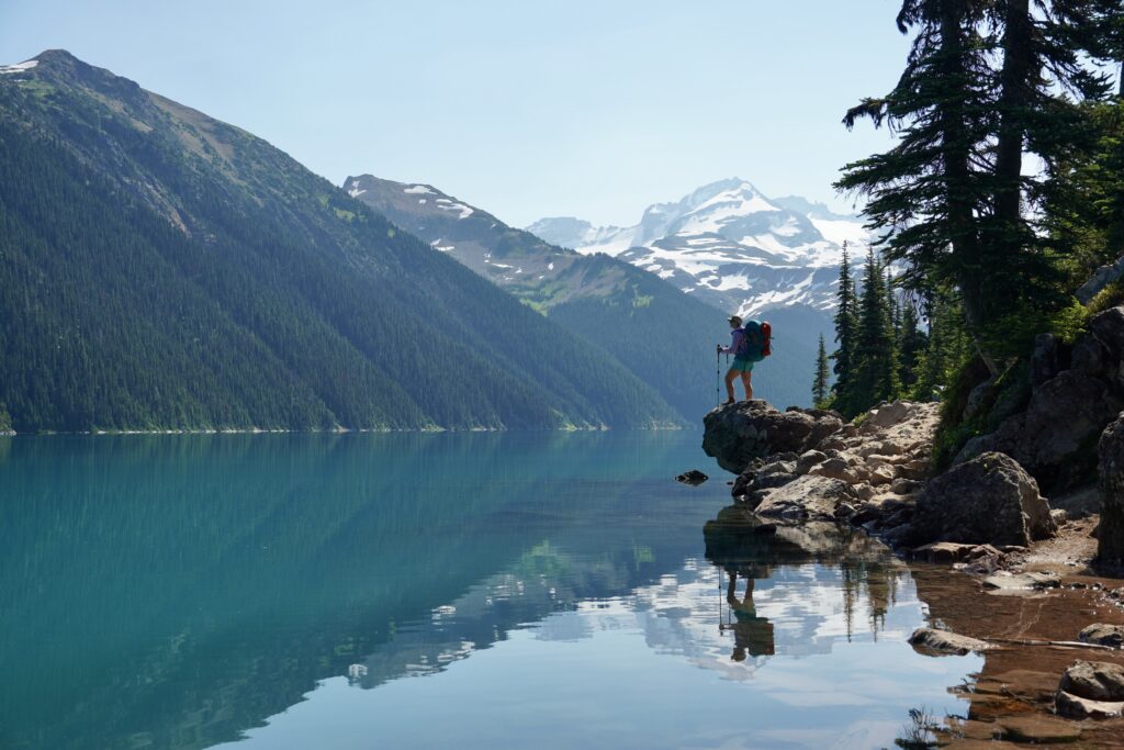 a mirrored image of a hiker and the mountains at Garibaldi Lake