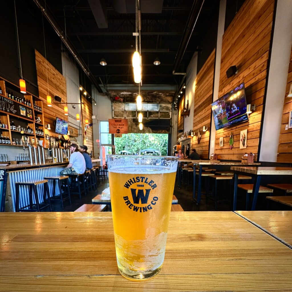 a Whistler Brewing Co Draft beer in front of their indoor seating