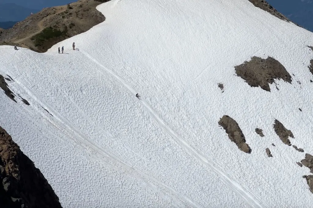 Someone sliding down the snow on their backpack.