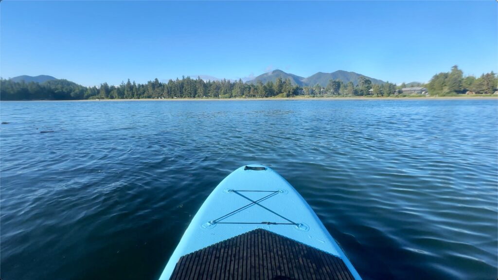 the tip of a blue paddleboard with view of MacKenzie Beach from the water