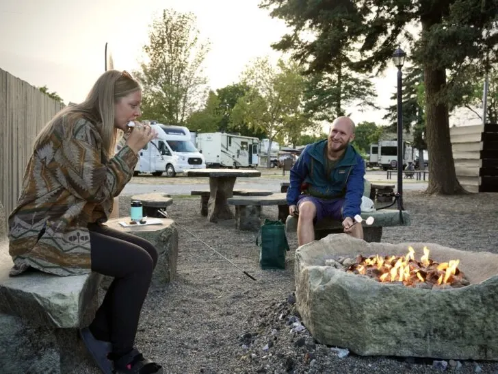 emily eating a smore and jake roasting a marshmellow around the communal campfire pit at the Spokane KOA Journey