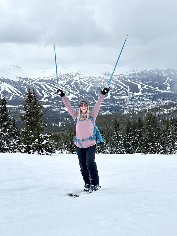 Skier poses in front of a ski resort.