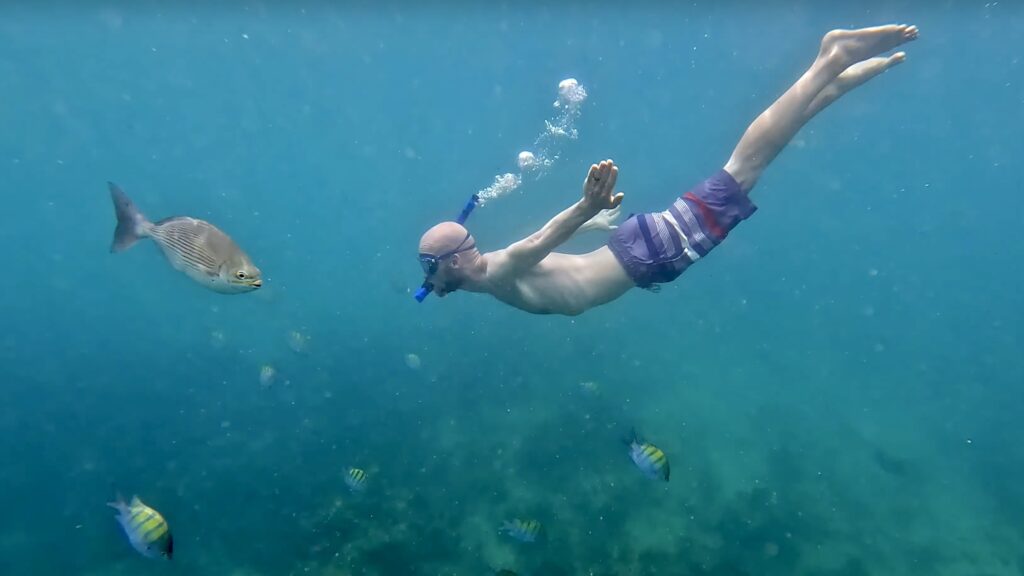 Jake free diving in Chileno Bay with fish surrounding him