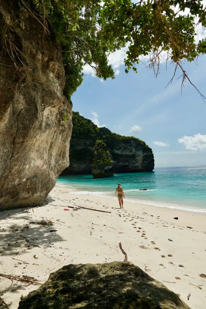 Emily walking in the sand toward the diamond shaped rock at the base of Suwehan Beach in Nusa Penida