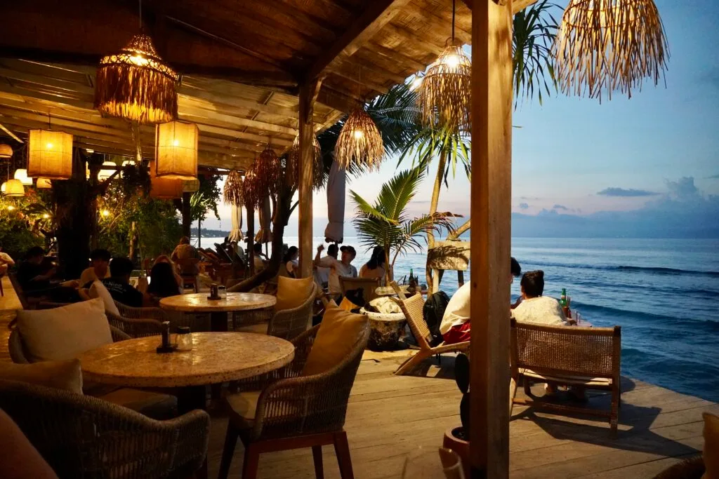 view of the restaurant at dusk inside Secret Penida, with boho lights, and views of the ocean