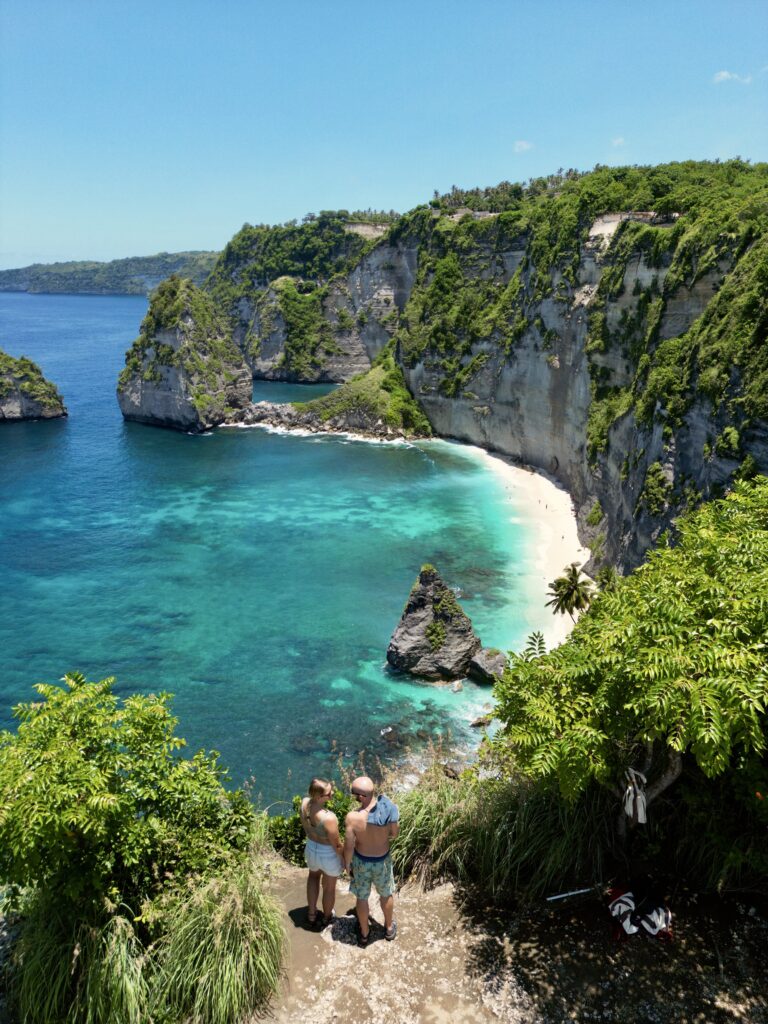 Jake and Emily holding hands at the cliffs edge looking out onto Diamond Beach