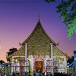 A temple in Chiang Mai glowing under a purple sunset sky